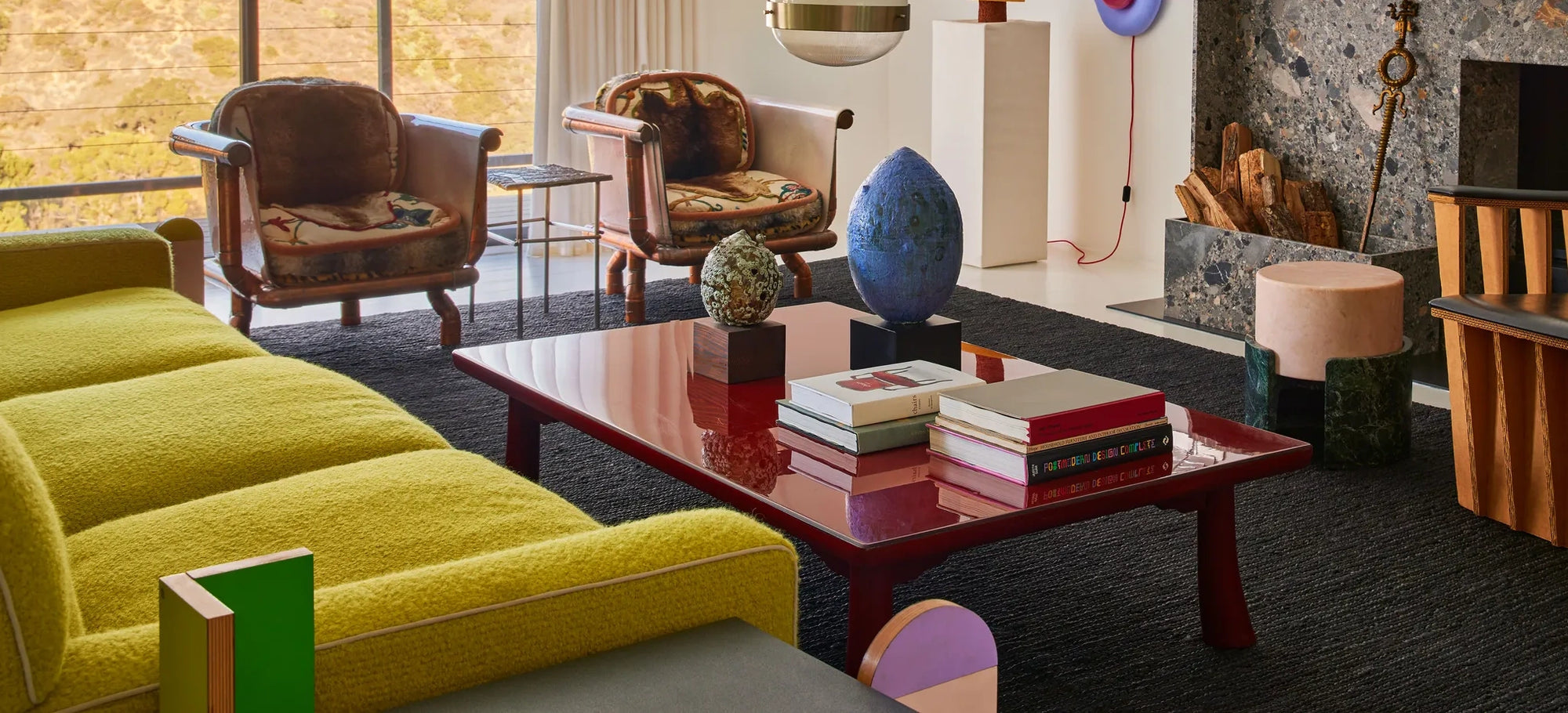 Modern living room with a yellow sofa, wooden chairs, and a coffee table with decorative items.
